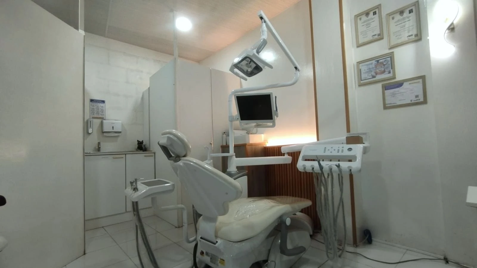 Consultorio de ORYM con sillón dental, monitor y diplomas